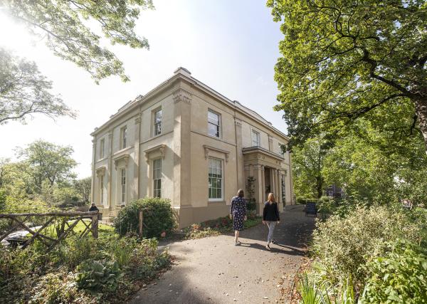 Elizabeth Gaskell's House in sunshine with two people walking up to it.