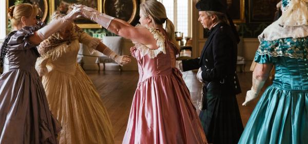 A picture of women dancing in period costume inside a country house (Temple Newsam)
