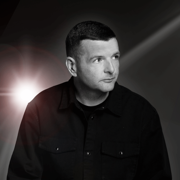 Kevin Bridges in a dark setting with a beam of light.