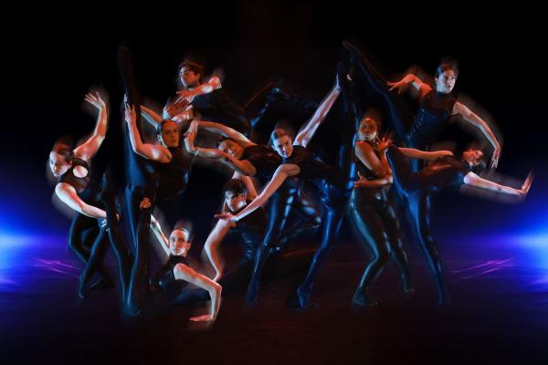 Group of dancers on stage with blue lighting and motion blur