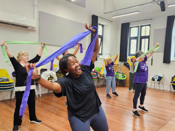A group of women dance with colourful scarves