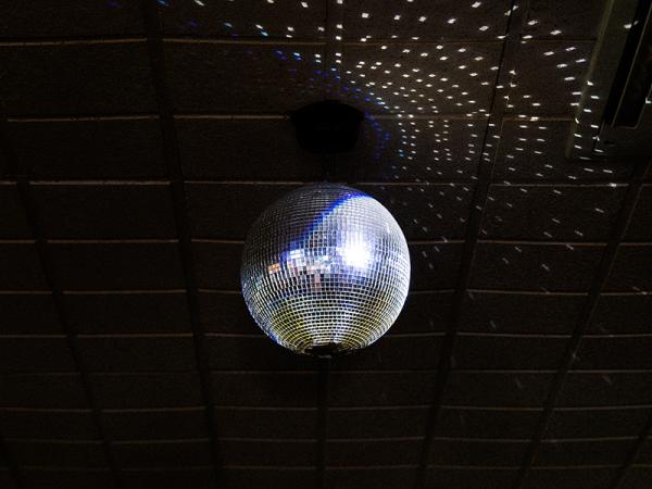 Disco ball on a dark ceiling, casting scattered light reflections.