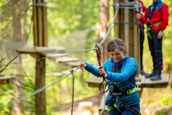 A person completing a high ropes course with a friend.