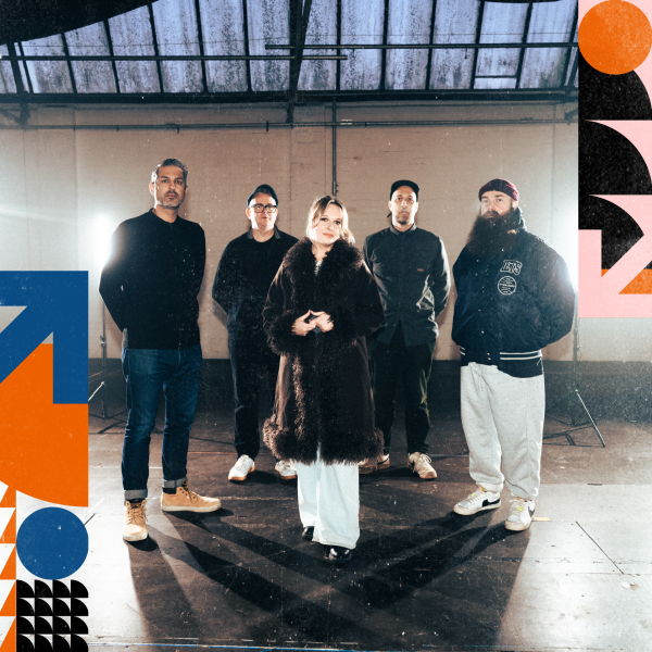 5 musicians standing in a warehouse