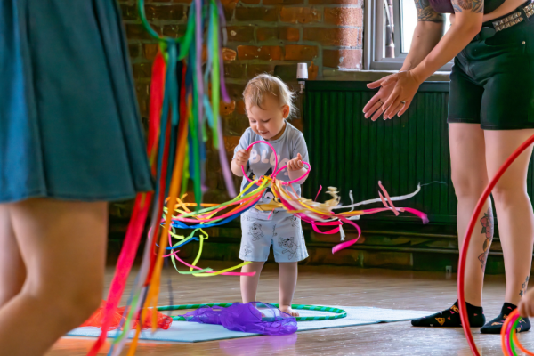 A small boy plays with coloured ribbons in a dance studio