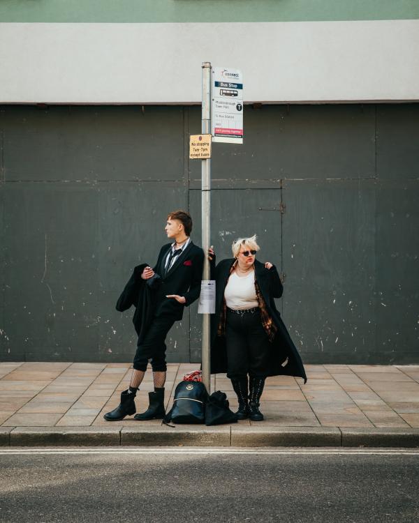 Two goths standing at a bus stop