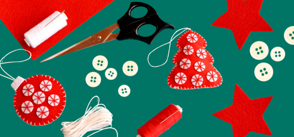 Festive craft materials - scissors, buttons and red and white baubles made from felt against a green backdrop