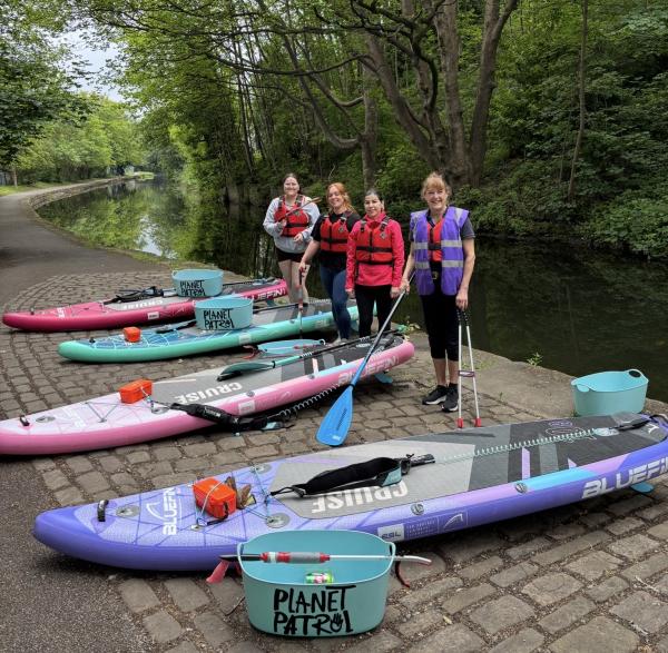 People excited to do a litter clean up with their equipment on paddle boards 