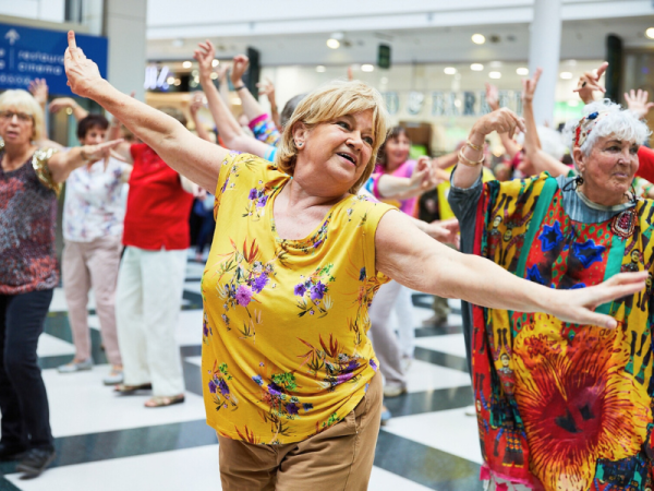 A lady in a yellow top is dancing with her arms outstrectched 