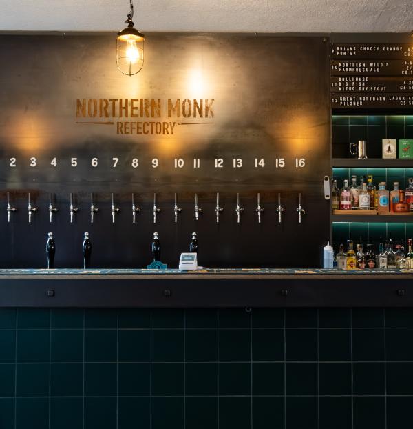 A view of the bar at Northern Monk Refectory Leeds, with green tiles and a steel back bar.