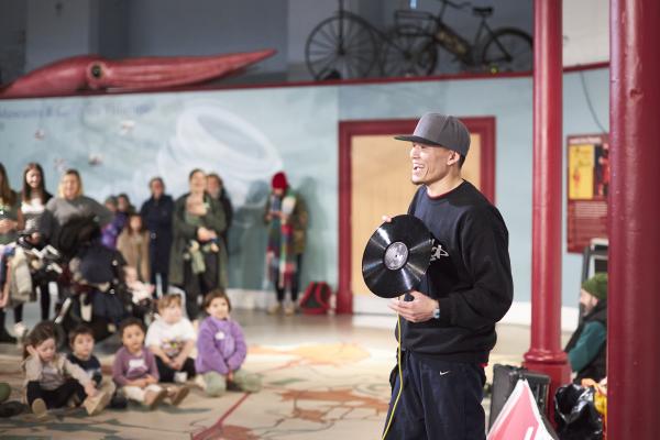 Man holding vinyl record, talking to an audience