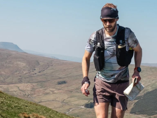 A man is climbing a hill and holding a map