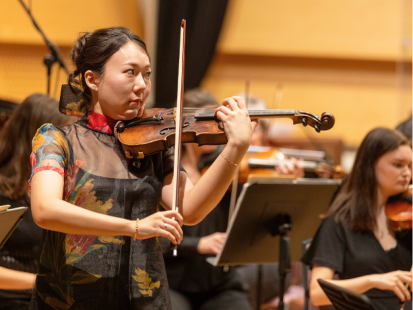 Young woman playing first violin in an orchestra.