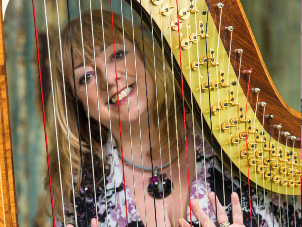 Press shot of Eira Lynn Jones standing behind her harp.