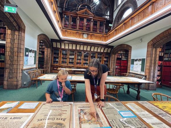 A child and a librarian looking at artefacts in Leeds Central Library