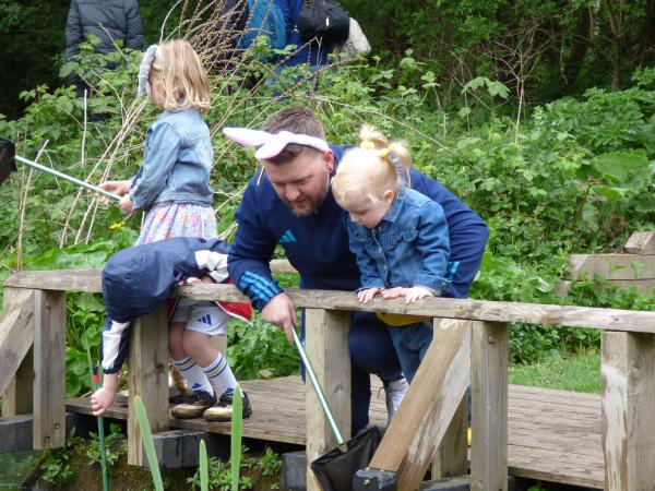 A father and two small girls pond dipping. Dad is wearing bunny ears.