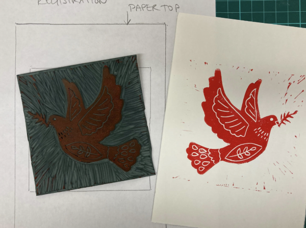 A card with a printed image of a dove in red ink alongside the linocut from which it was taken