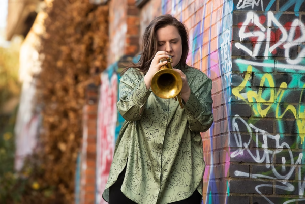 A woman in a green shirt playing a flugel horn.