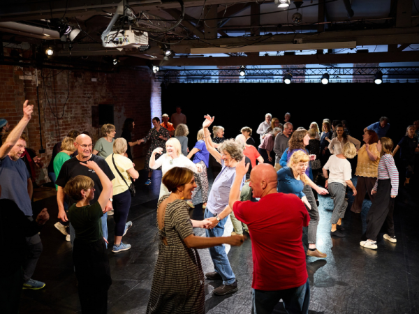 A group of people dance freely together in a studio