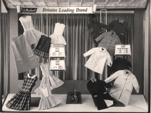 Black and white photo showing a window display of children's clothing