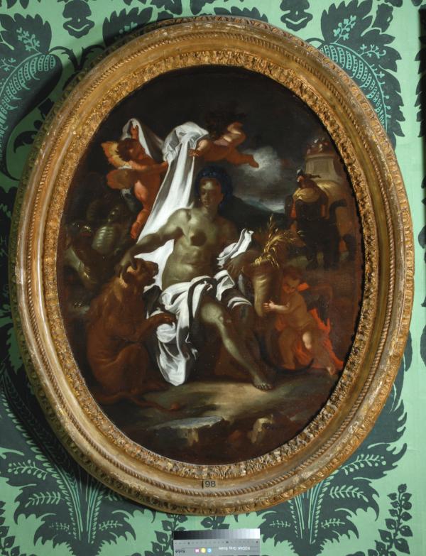 An oval frame hung on green patterned wallpaper. The frame picture is Africa by F Solimena