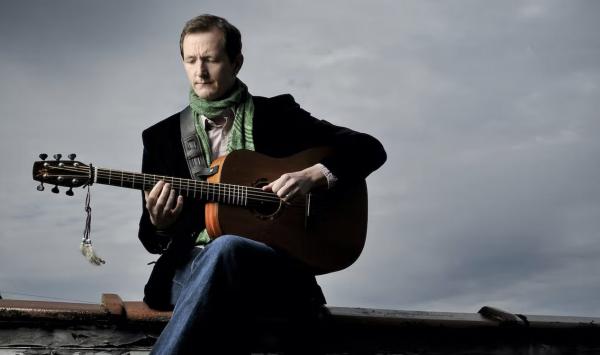 Man wearing black blazer playing guitar