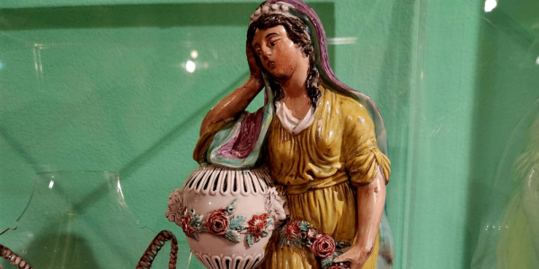 A close up image of a ceramic woman looking mournful