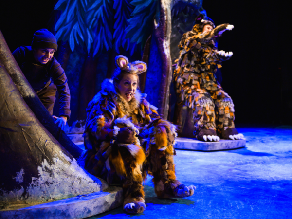 A person dresses as a mouse sits at the front of a snowy stage