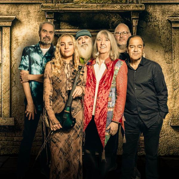 The members of Steeleye Span stand together in front of a sepia-toned building.