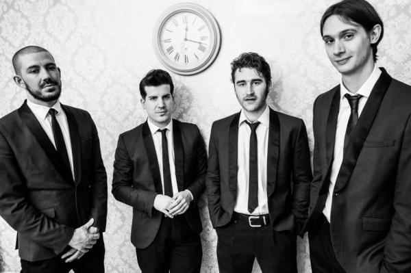 Black and white image of 4 smart men in black suits. 