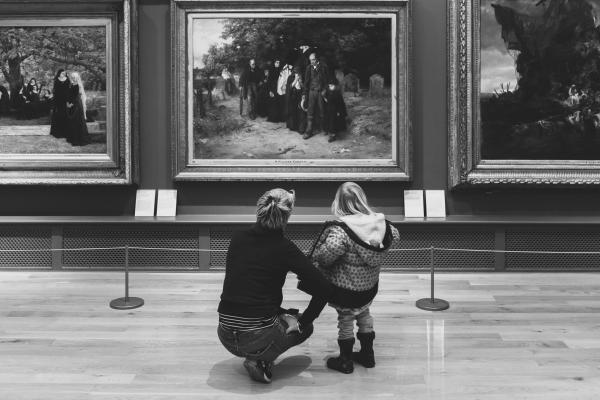 An adult and a young person in front of an artwork in a gallery
