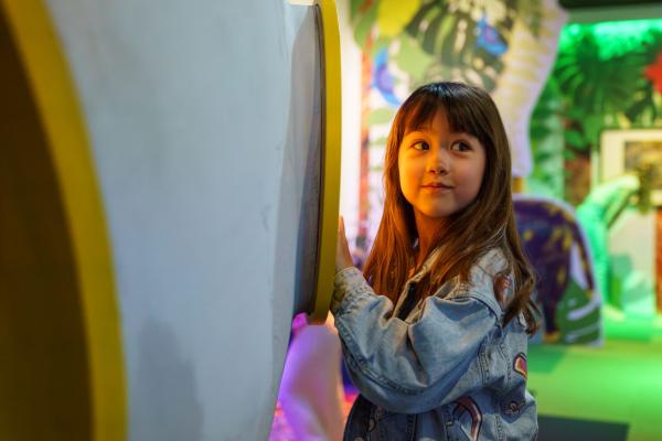 A young child standing outside a colourful room