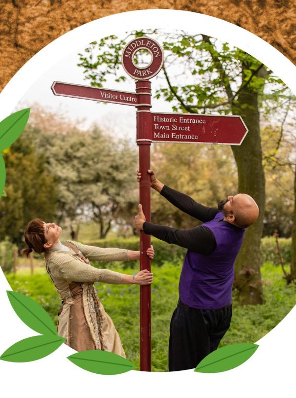 two dancers in Indian costumes at a Middleton Park sign post.