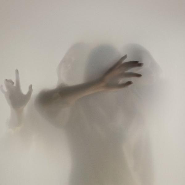 Three faint figures with outstretched arms reach out through thick grey mist.