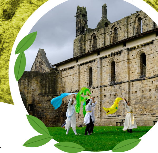 A yellow-green, nature-themed flyer promoting Six Seasons: Architecture of Nature, an artist-led walk organised by Balbir Singh Dance Company at Kirkstall Abbey in Leeds.  The flyer features a woodland background in shades of yellow and green, large white lettering, light blue hiIn front of Kirkstall Abbey, four performers dressed in white are moving…