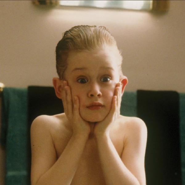 Still from Home Alone, with a young boy in a bathroom with slicked back hair and two palms held to his face, pulling a shocked expression in the mirror with raised eyebrows.
