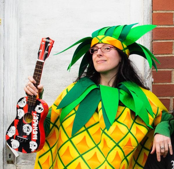 Nick Bray dressed in a pineapple costume, holding a ukulele