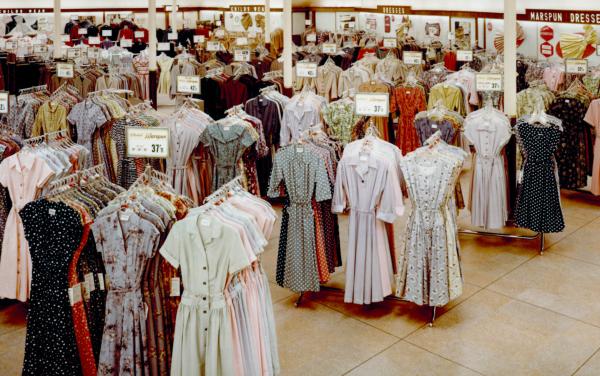 Colour photograph of a store interior with rails full of dresses