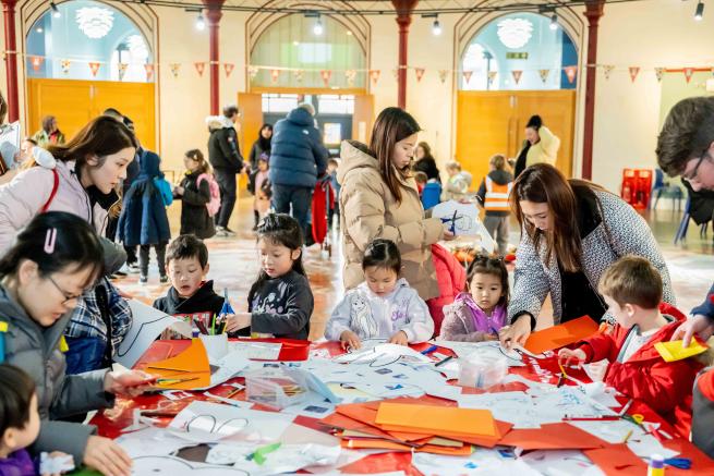 A crafting table surrounded by children and families