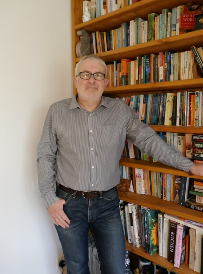 Photograph of author J.R Ellis standing by a bookcase