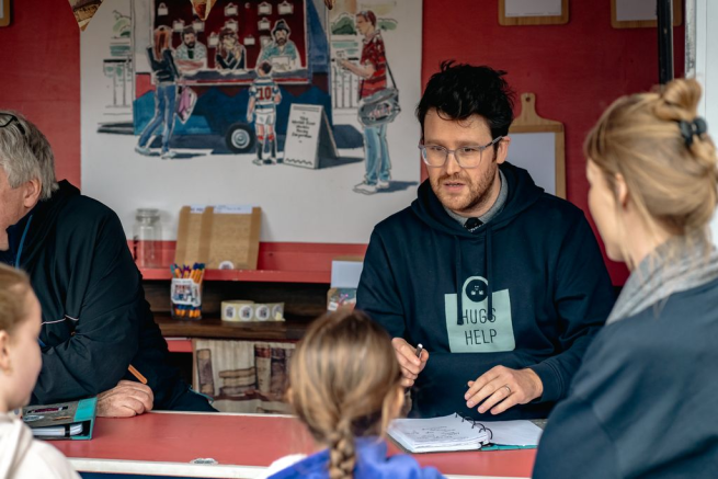 A poet wearing a hoodie talking to family
