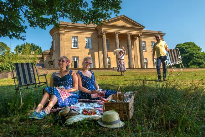People having a picnic on the grass outside the Mansion at Roundhay Park