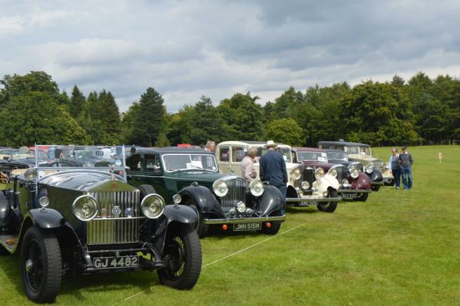  Collection of classic cars parked in field.