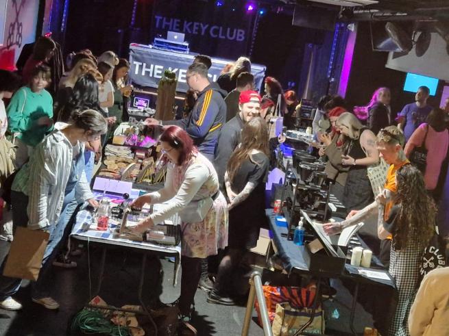image shows a busy market inside The Key Club with stalls setup and lots of people browsing.
