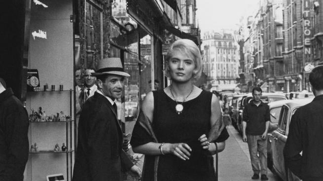 A black and white shot of a well dressed woman walking down the streets of Paris, turning heads. 