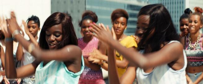 A group of young black women dance on top of a rooftop in Paris. 