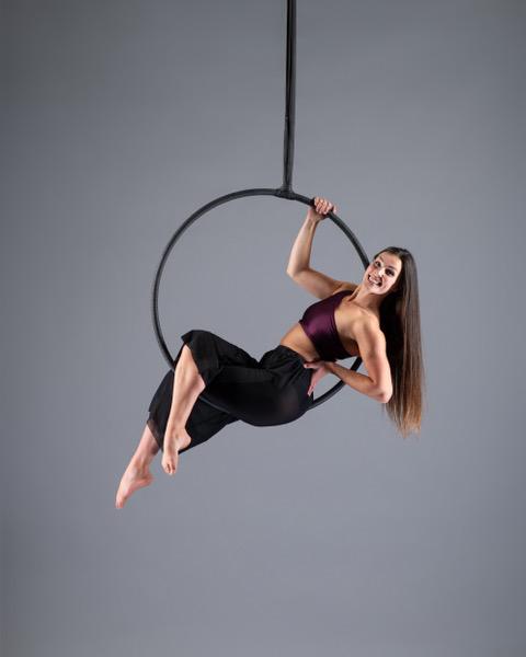 Studio photoshoot, Jess in sat and laid back in a hoop that's hanging from above, she' smiling and looking to the camera