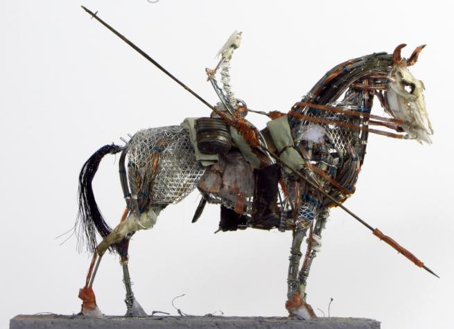 Side view of man with spear on horse.