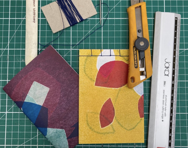 Image shows a selection of notebooks and bookbinding tools resting on a cutting mat
