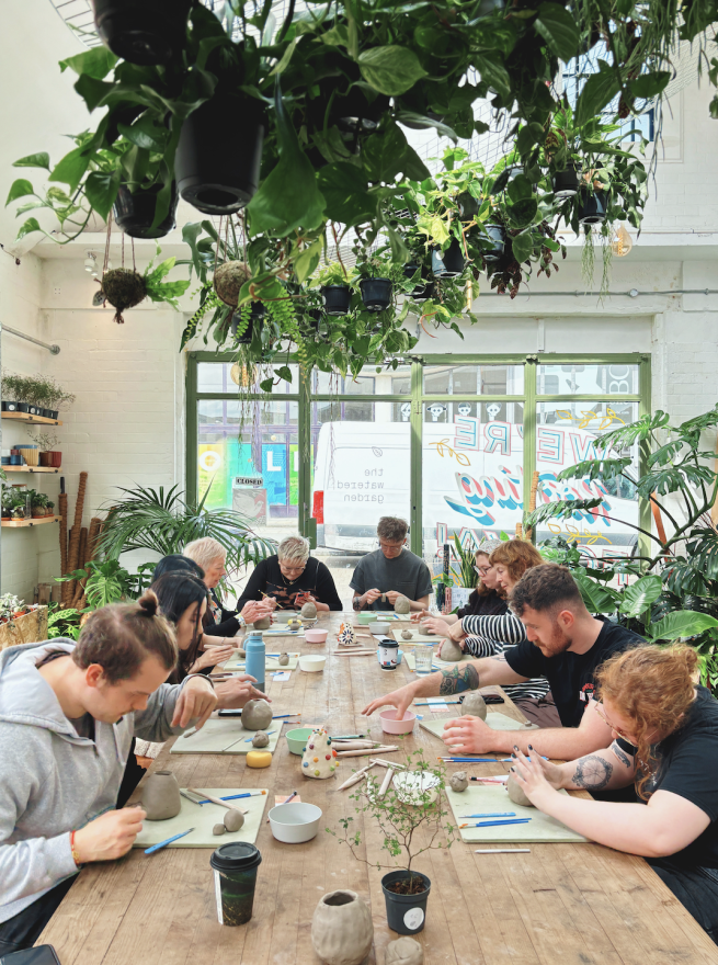 A group around a table being guided through the patterned mug workshop